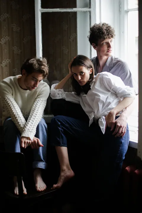 Three adults sharing a quiet moment by a window